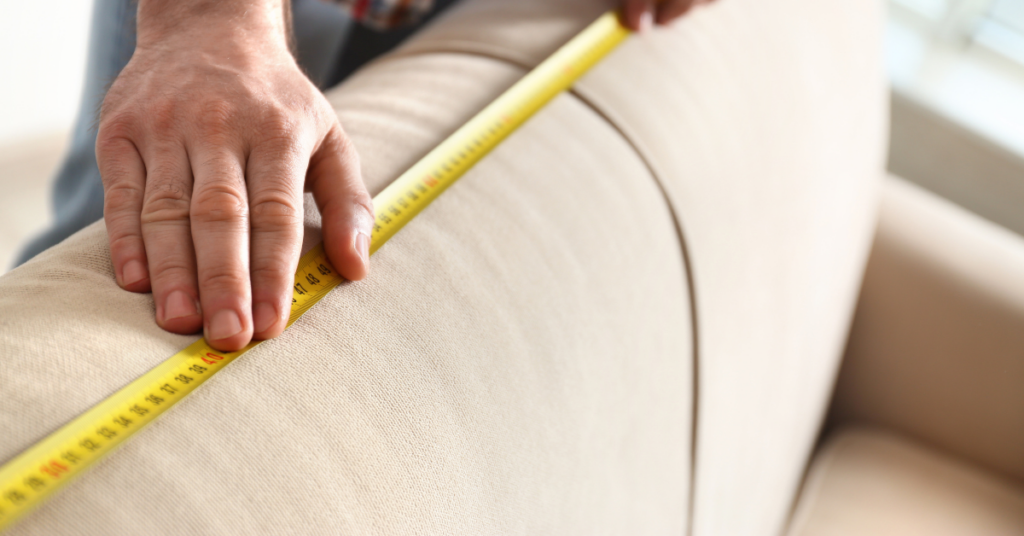 A person measuring a recliner using a tape measure